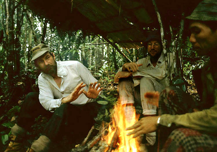 Anthony 'Tony' Howarth with Iban men, around campfire in Borneo